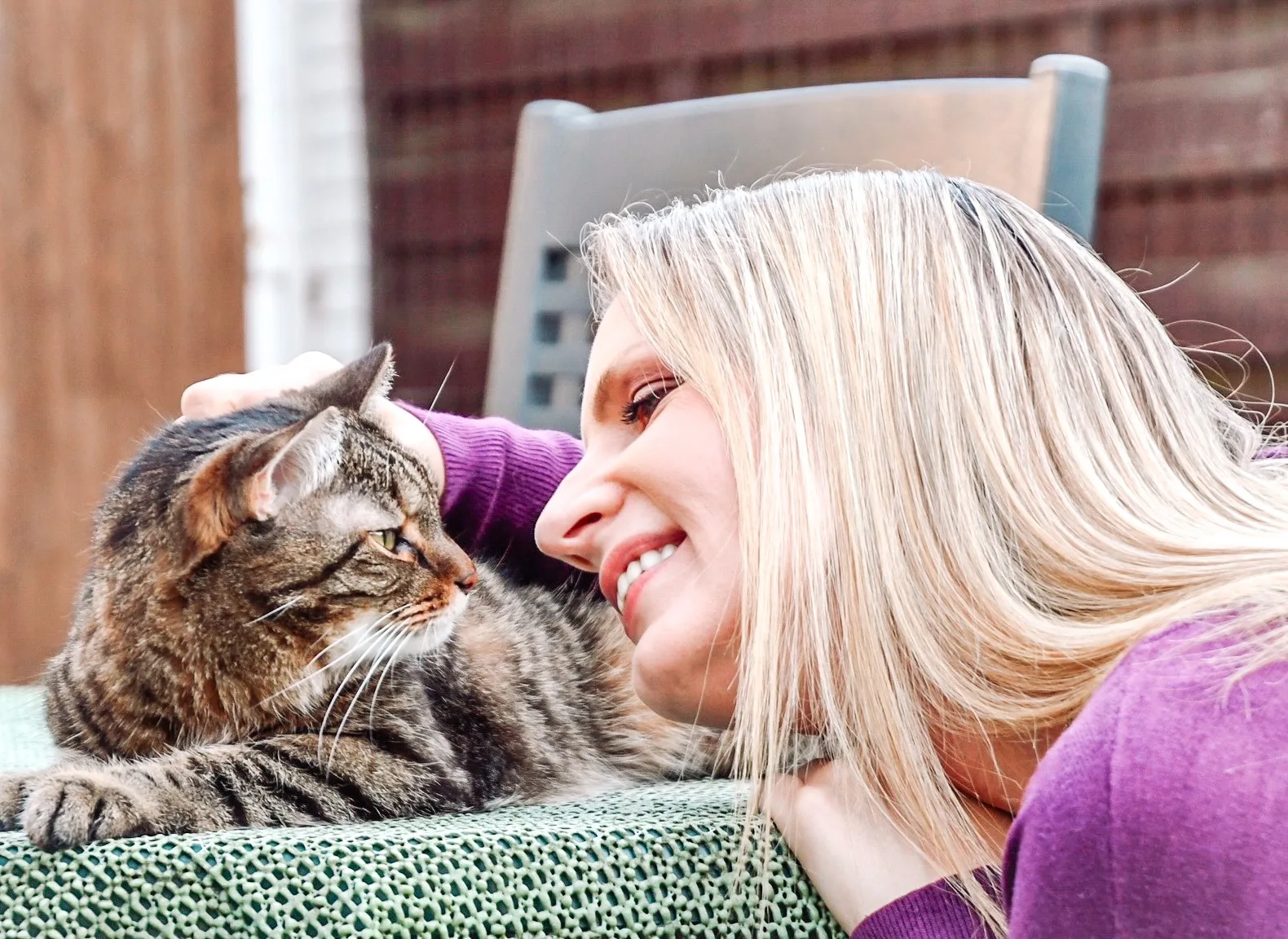 Jessica Koß draußen, Wange an Wange mit einer getigerten Katze